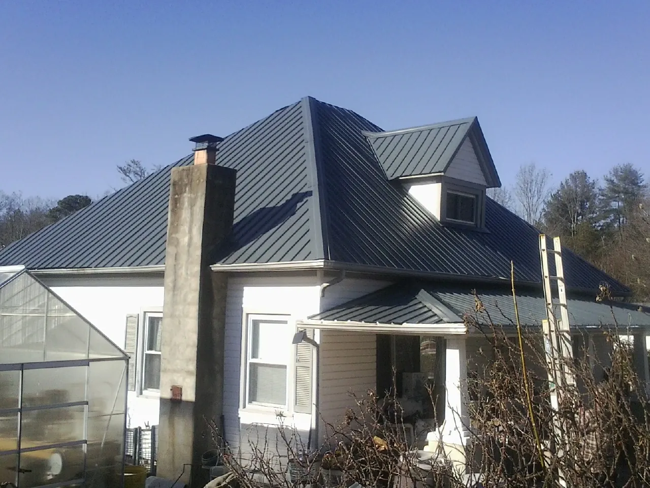 Dark blue standing seam metal roof on a white farmhouse with dormer — Slate & Tile Roof Repair by Roofing Brothers in Brewerton