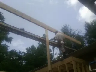 Carpenter setting a ridge beam over a new addition frame — Ice Dam Removal by Roofing Brothers in Brewerton