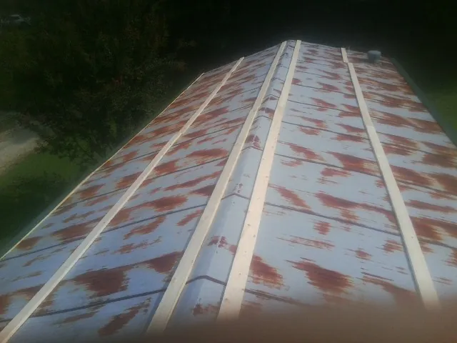 Rusted metal roof panels with new wood purlins before replacement — Storm Damage Roof Repair in Brewerton by Roofing Brothers