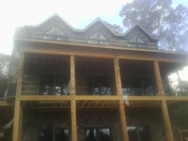 Dormers and porch framing on a large log home under construction — Roof Coating work by our crew in Brewerton