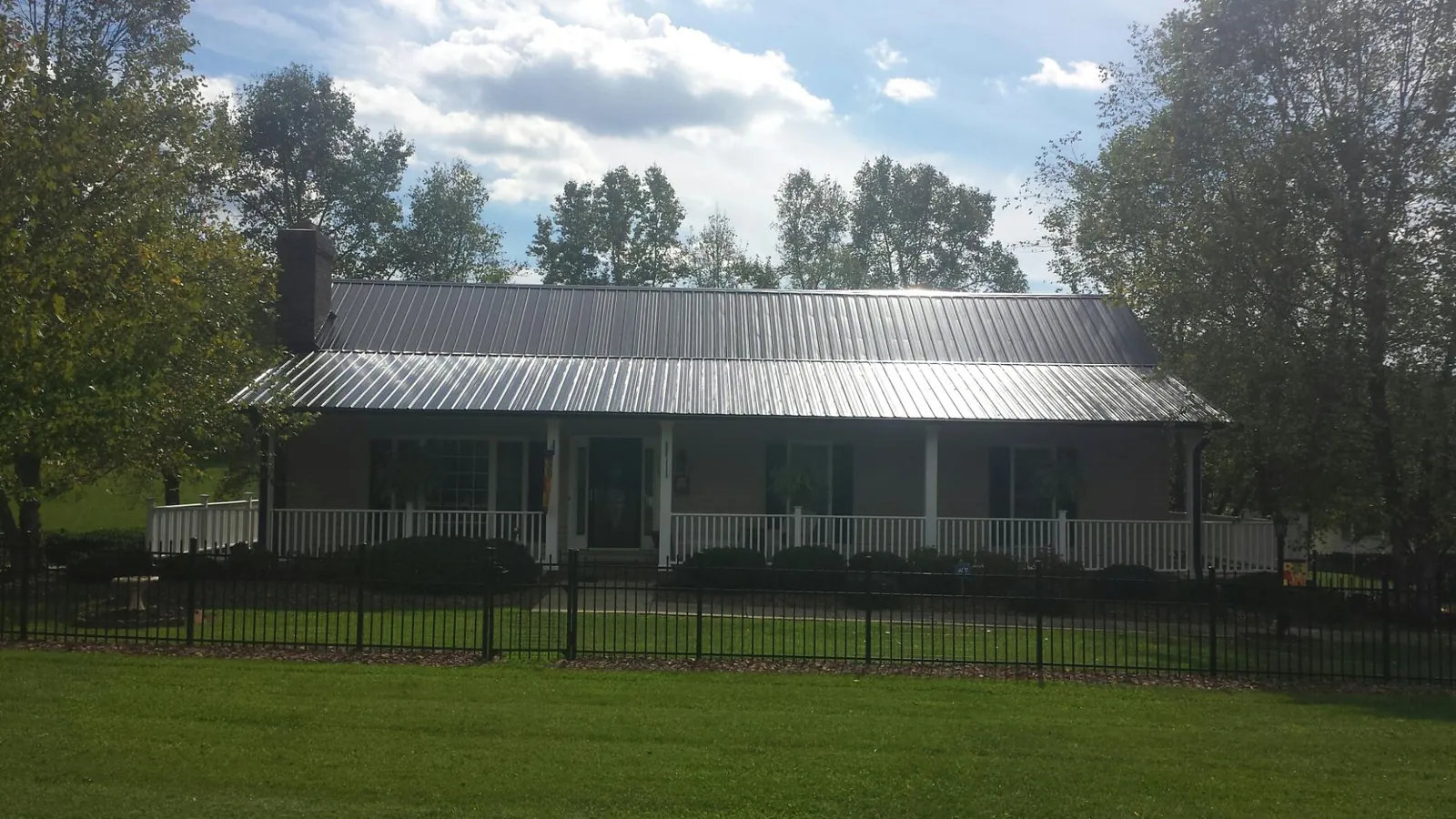 Gray metal roof on a brick ranch with a full width front porch — Gutter Guard Installation work by our crew in Brewerton