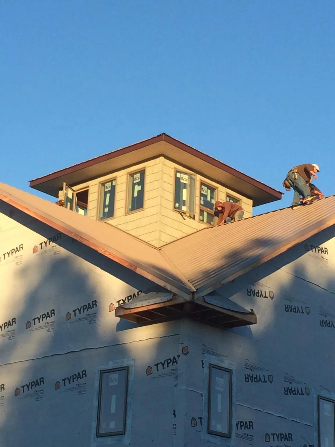 Roofers working around a rooftop cupola on a new metal roof at sunset — Roof Waterproofing in Brewerton by Roofing Brothers